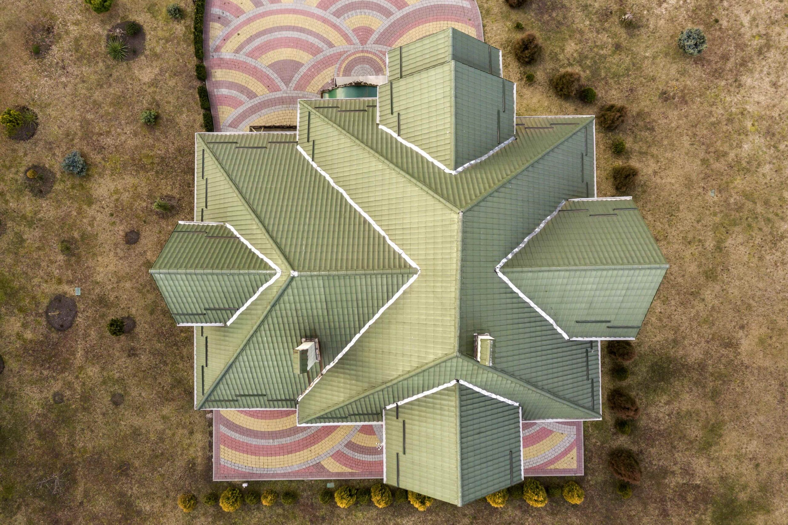 Aerial top view of new residential house cottage with shingle roof on fenced big yard on sunny day.