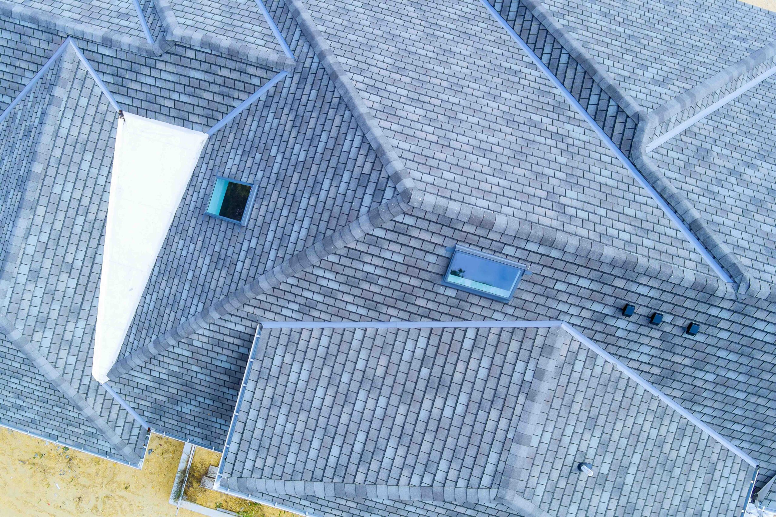 Construction roof of new house is being covered with asphalt shingles while building