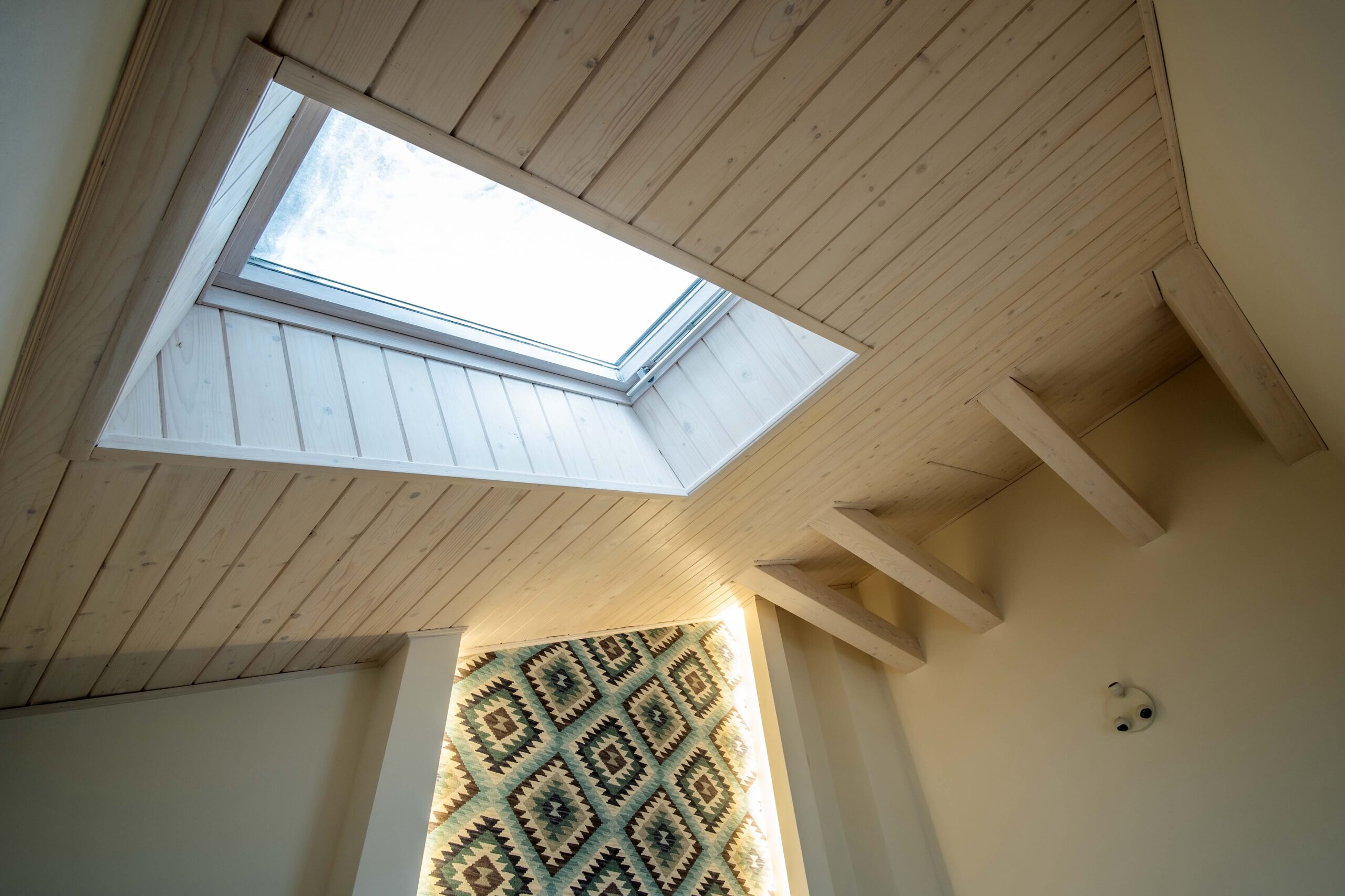 Wooden ceiling in a contemporary mansard room with attic window of decorative planks surface.
